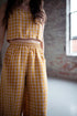 Person wearing a yellow gingham outfit in a room with a window and floral rug.