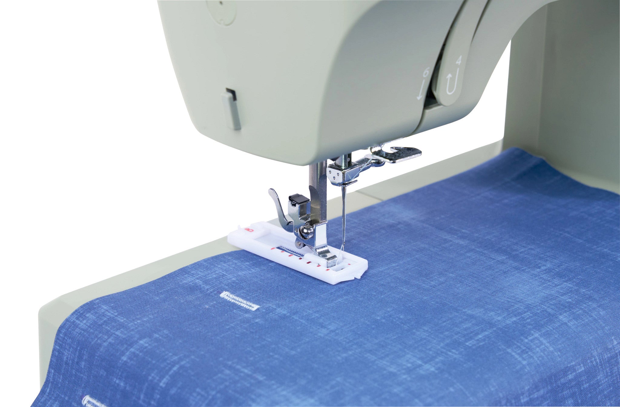 A close-up of a sewing machine presser foot and needle guiding a blue woven fabric over a light gray machine bed on a white background.