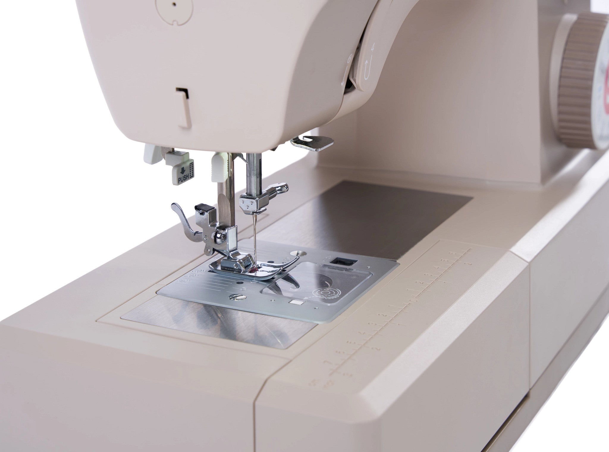 Close-up of a cream-colored sewing machine showing the needle area, presser foot, metal plate, and part of the upper housing against a white background.