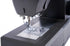 Close-up of a dark gray sewing machine showing the needle area, presser foot, and metal feed dog plate against a white background.