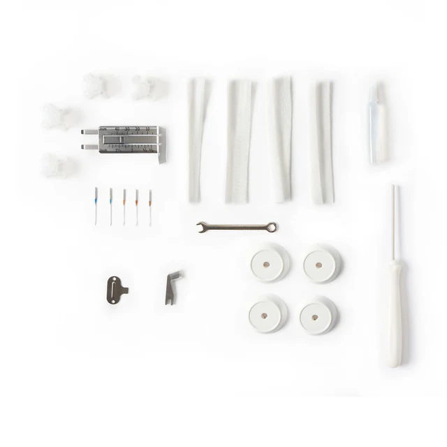 A multi-piece kit of white and silver plastic tools and components, including several white cylindrical tubes, four round white discs, a small metal wrench, a white-handled screwdriver, and several small colored resistors, laid out on a plain white background.