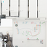 Close-up of a white sewing machine showing the upper needle area and a printed thread path diagram on the front panel with colored line illustrations.