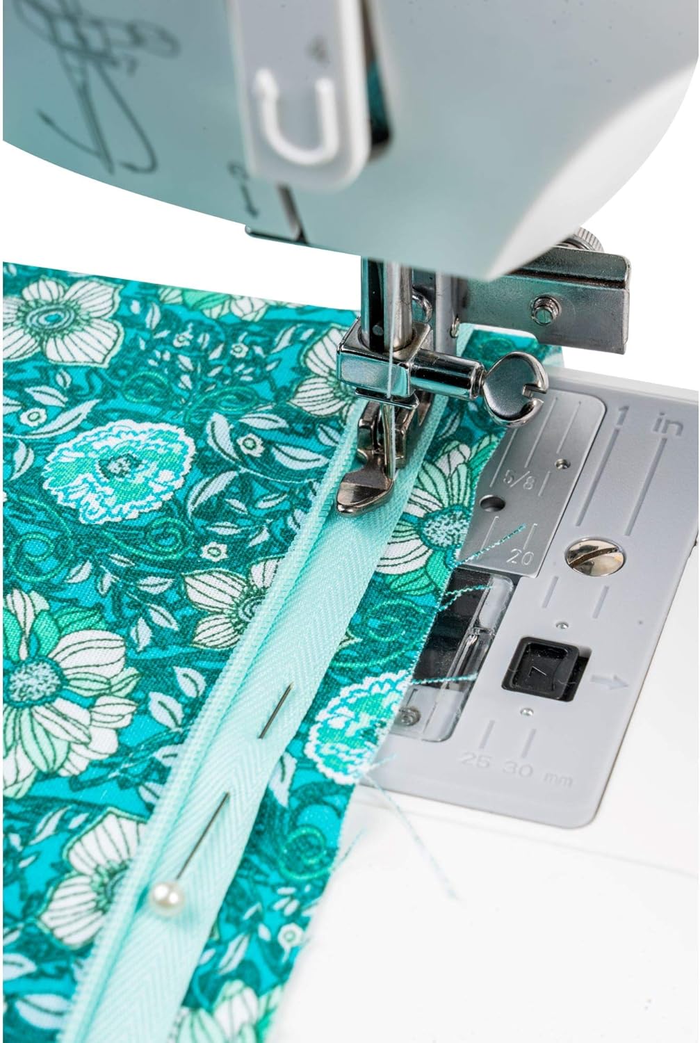 Sewing machine needle stitching turquoise fabric with floral pattern