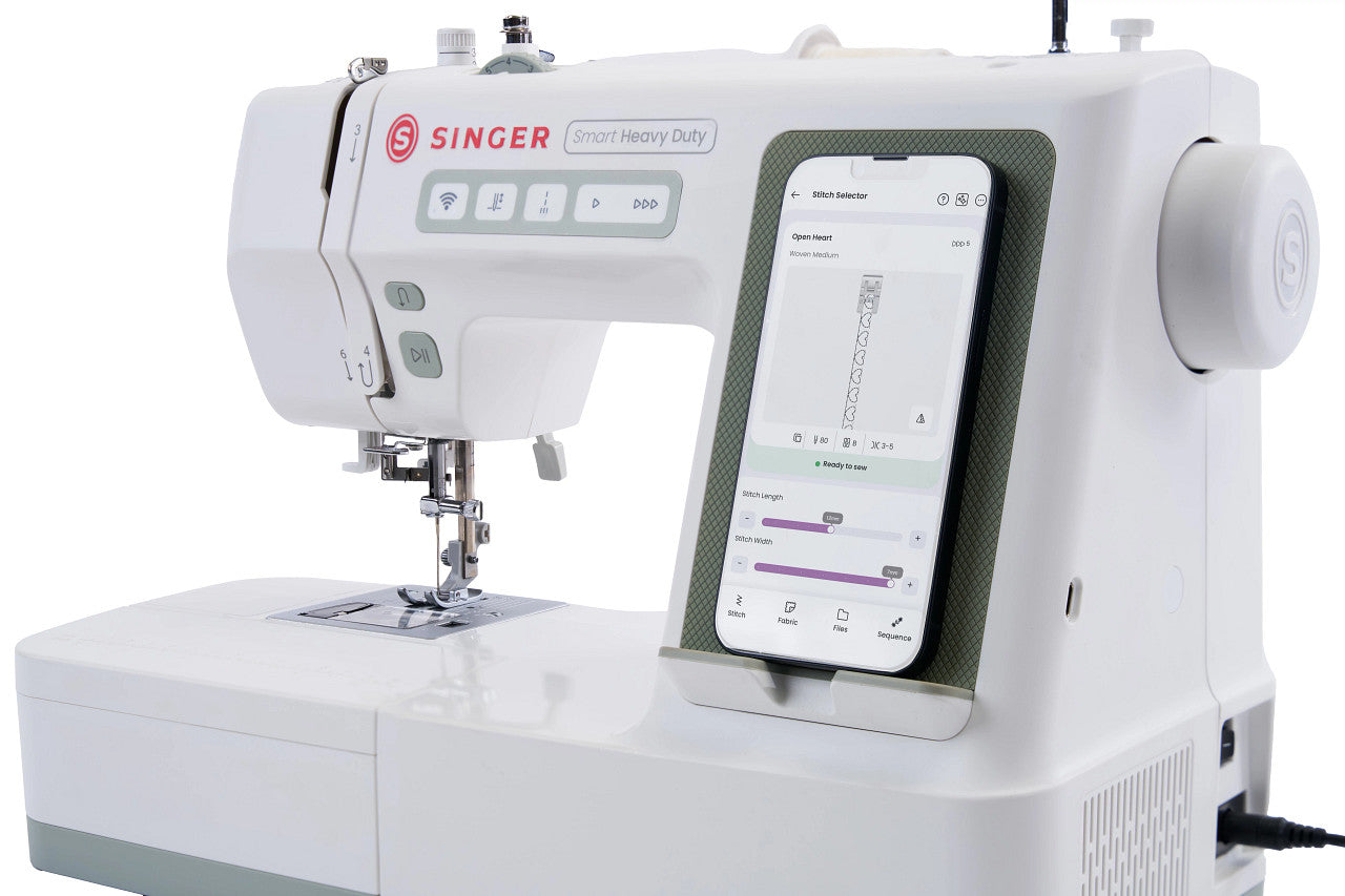 A white Singer Smart Heavy Duty sewing machine with a built-in smartphone display showing an app interface, photographed on a clean white background.