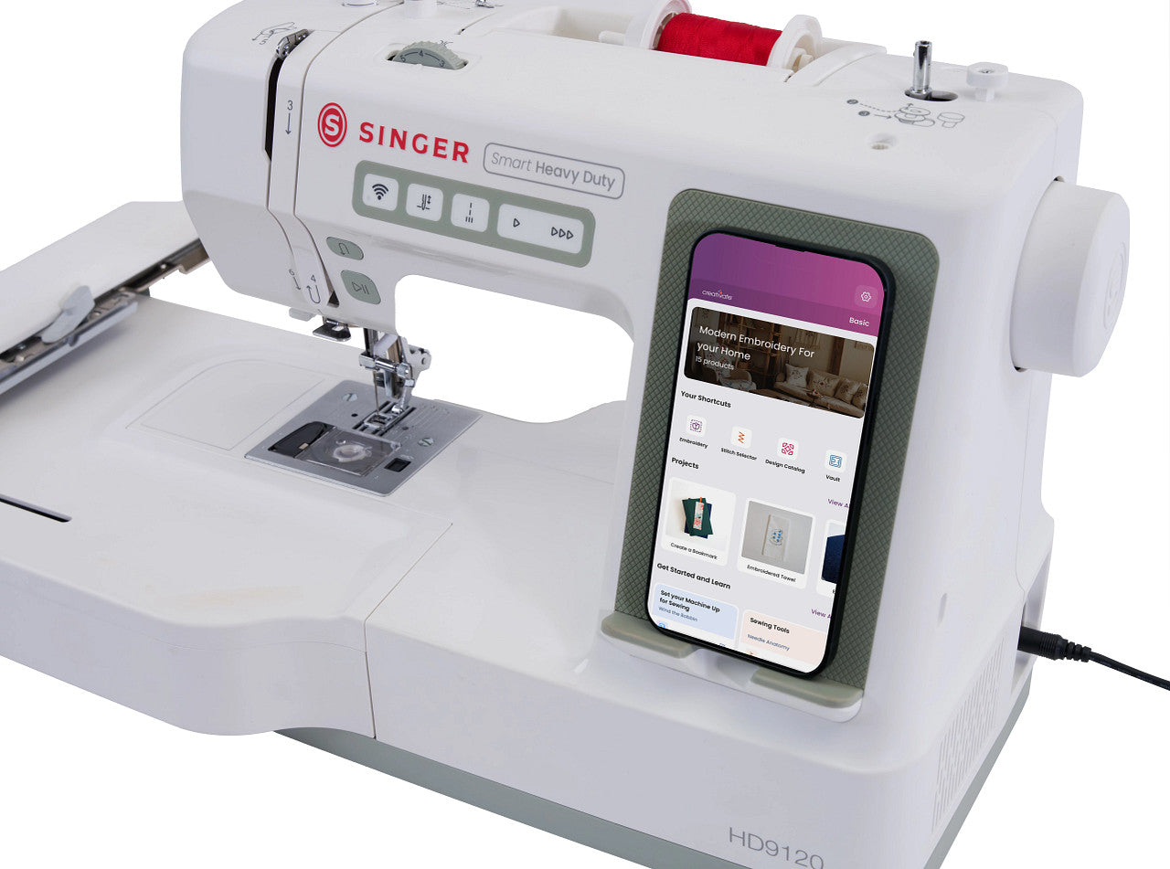 A white Singer sewing machine with a built-in smartphone display showing a sewing app, photographed on a clean white background.