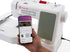 A hand holds a smartphone displaying a sewing app interface in front of a white Singer Smart Heavy Duty sewing machine on a clean white background.