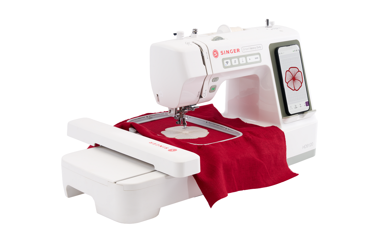 A white Singer embroidery machine with a digital touchscreen display, shown with a red fabric hoop insert and a red fabric piece under the needle, isolated on a white background.