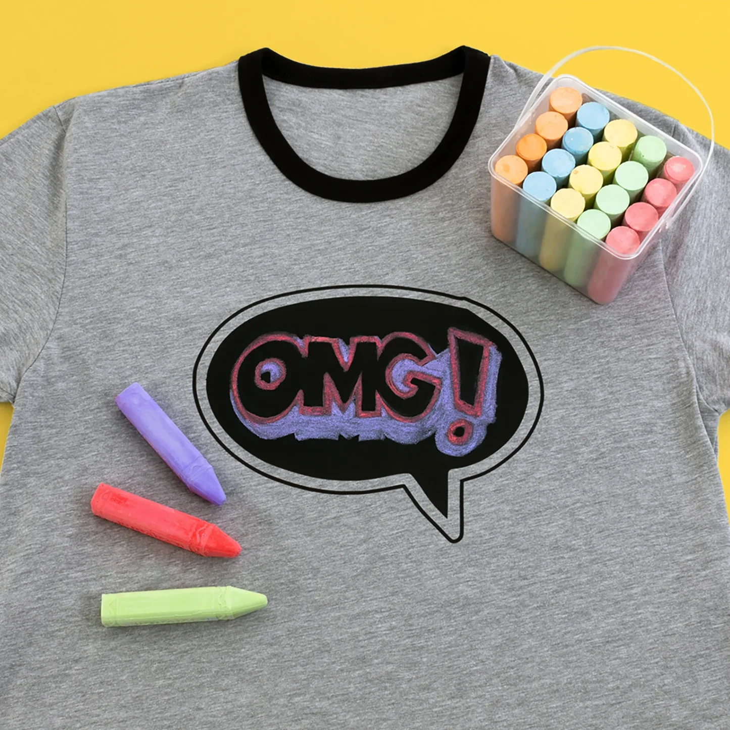 Gray t-shirt with 'OMG!' design and colorful chalks on a yellow background