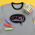 Gray t-shirt with 'OMG!' design and colorful chalks on a yellow background