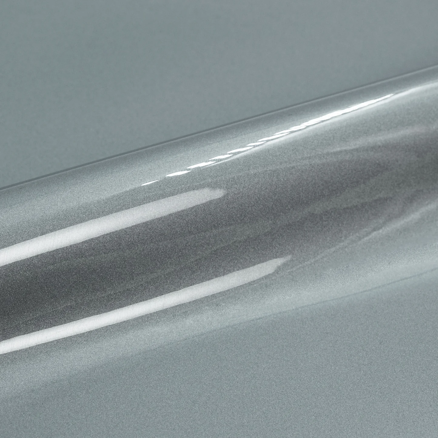 Close-up of a roll of silver reflective vinyl wrap on a gray background