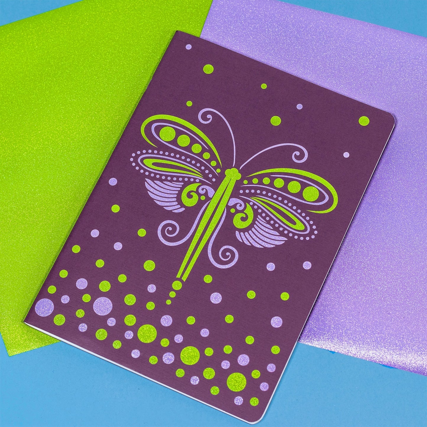 Notebook with a green dragonfly design on a colorful background