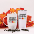 Two white mugs with text 'A Cup of Joe for the Home' and 'A Cup of Joe for the Road' against a background of autumn leaves and coffee beans.