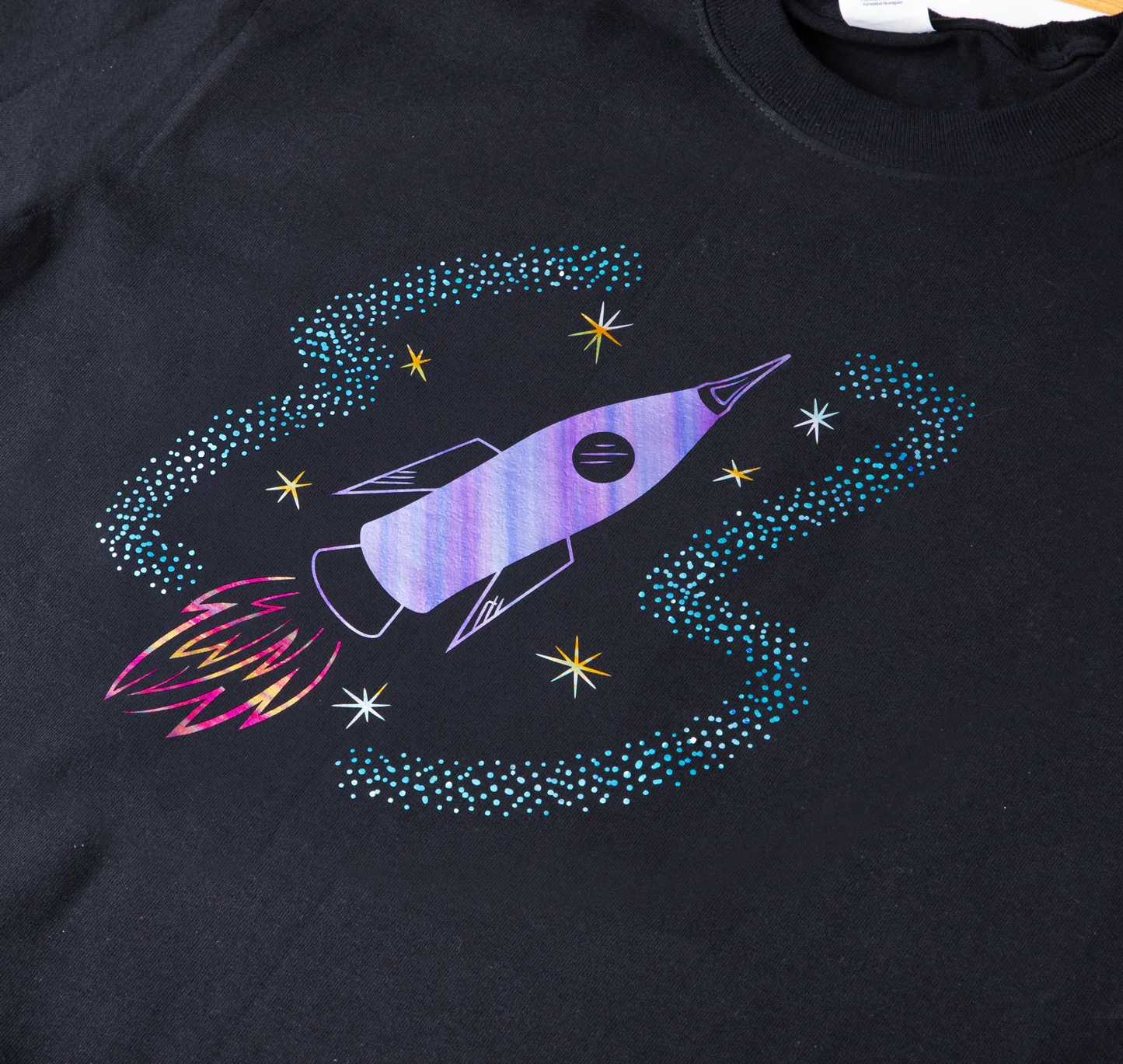 Black t-shirt with a colorful space-themed design featuring a rocket ship and stars.