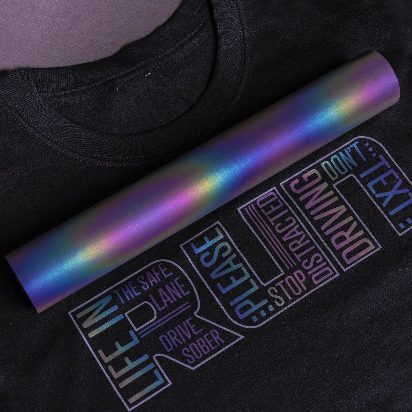 Black t-shirt with text and a colorful roll of vinyl on top