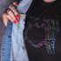 Person wearing a black t-shirt with a colorful skeleton hand design, holding a denim jacket.
