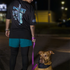 Person walking a dog on a leash at night with a dark background
