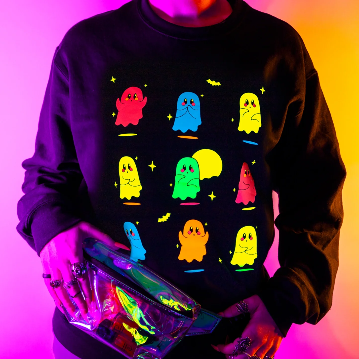Person wearing a black sweatshirt with colorful ghost designs on a gradient background