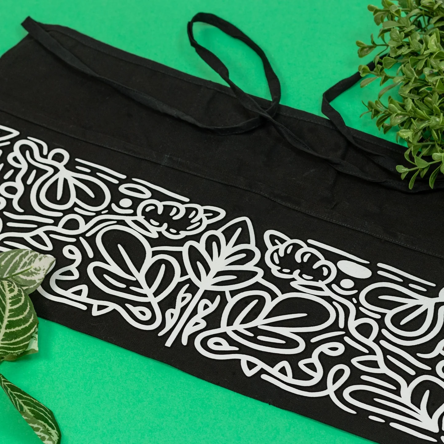Black apron with white floral patterns on a green background