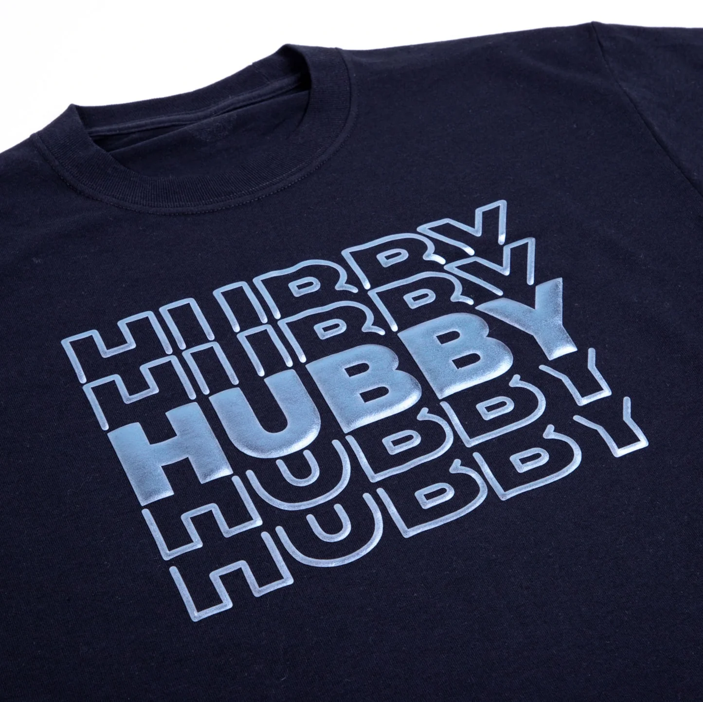 Black t-shirt with 'HUBBY' text in metallic blue on a white background
