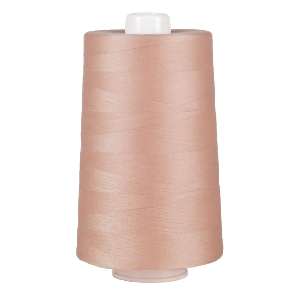 Spool of light peach thread on a white background