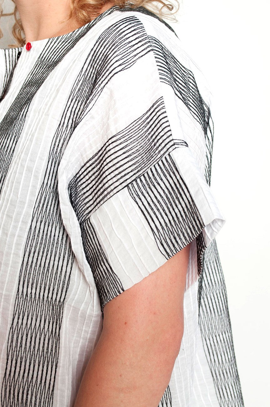 Close-up of a person wearing a white shirt with black geometric patterns.