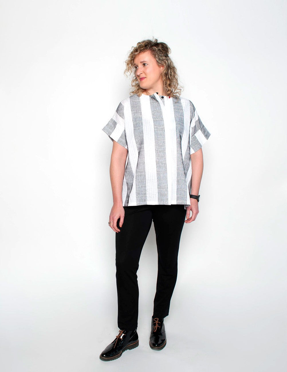 Person wearing a black and white striped shirt with black pants on a white background