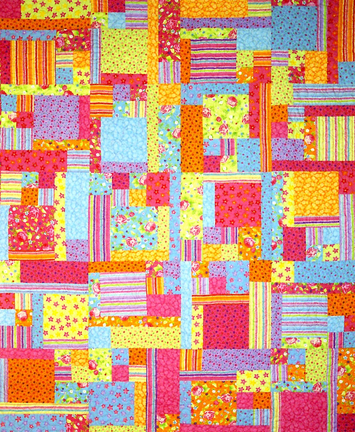 A colorful patchwork quilt featuring a variety of fabric patterns including stripes, florals, and solid colors in shades of pink, yellow, orange, blue, and red.