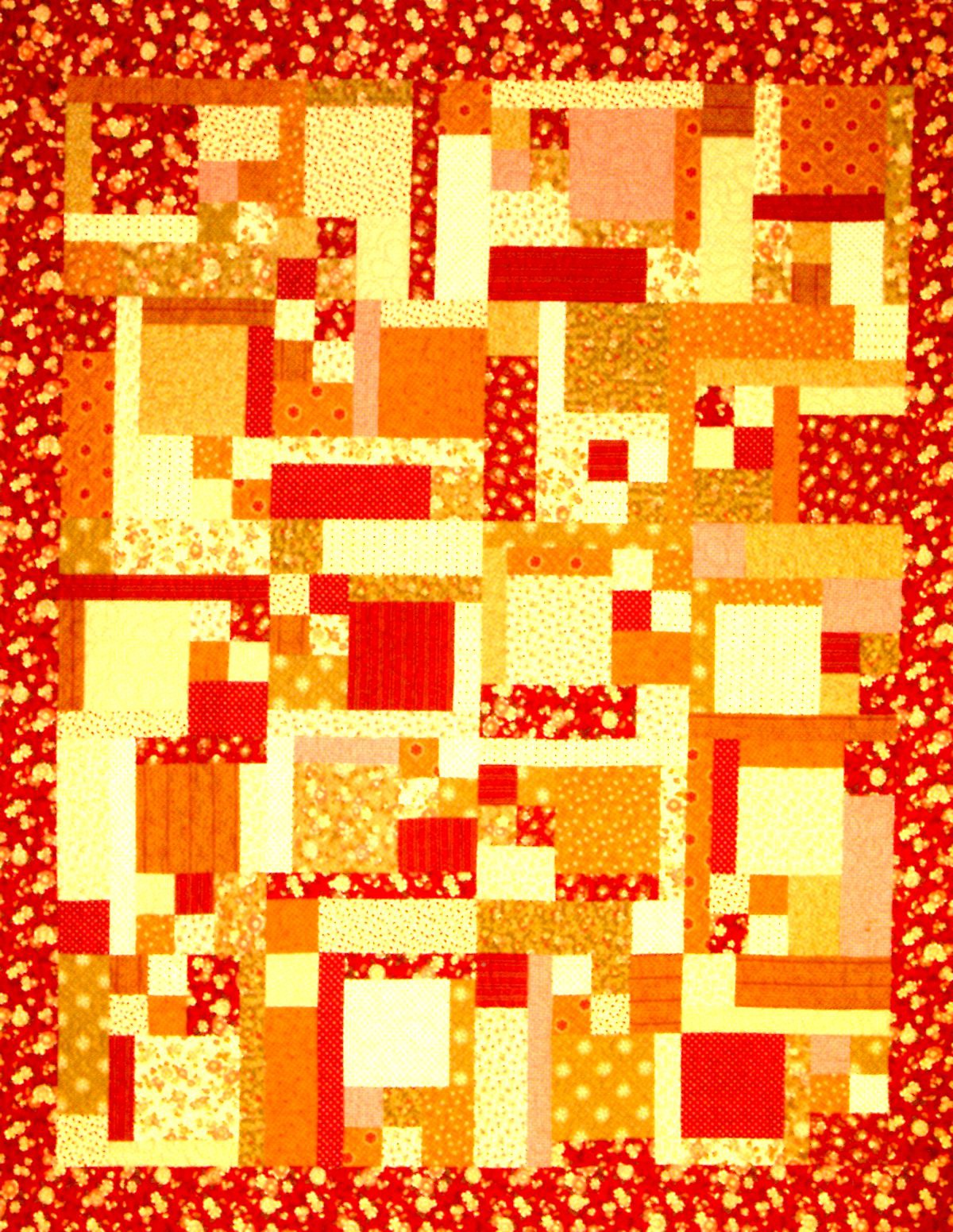 A square patchwork quilt featuring a vibrant abstract design in shades of red, orange, yellow, and cream, finished with a red floral border.