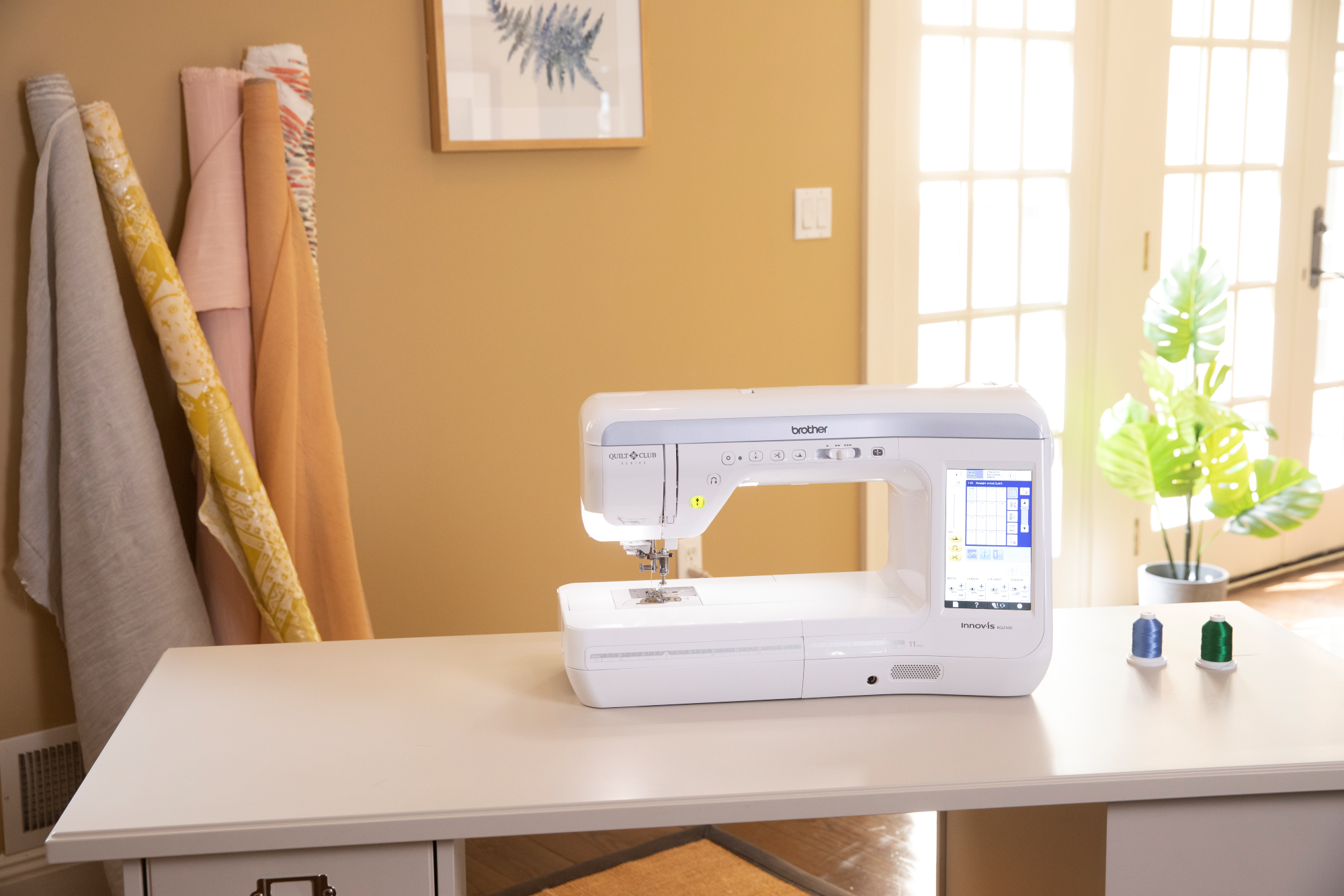 image of the Brother Innov-is BQ2500 eleven and a quarter inch Sewing and Quilting Machine on a table with sewing supplies