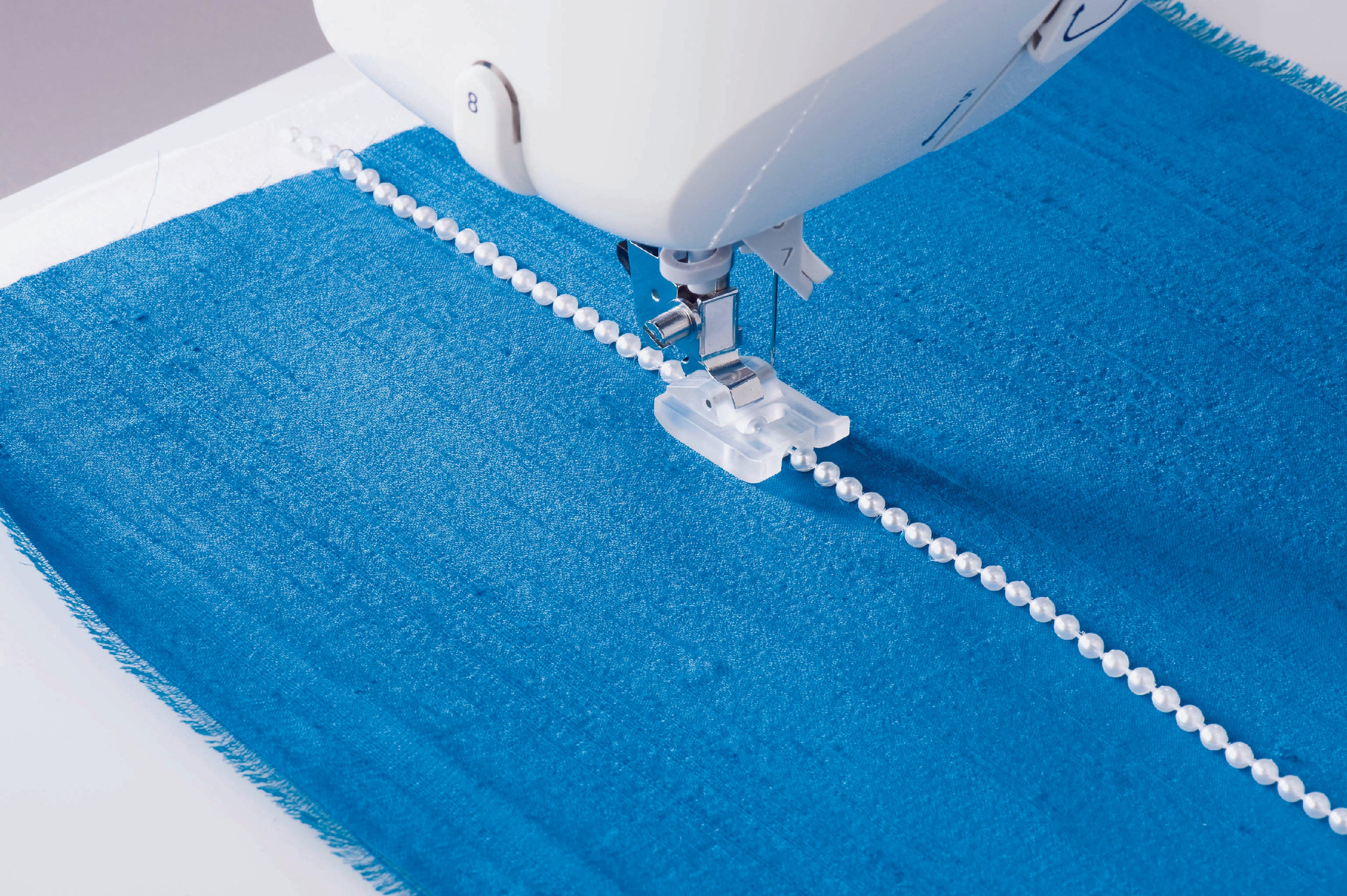 image of the JUKI HZL-NX7 Kirei Professional Quality Sewing and Quilting Machine being used to sew pearls into an item