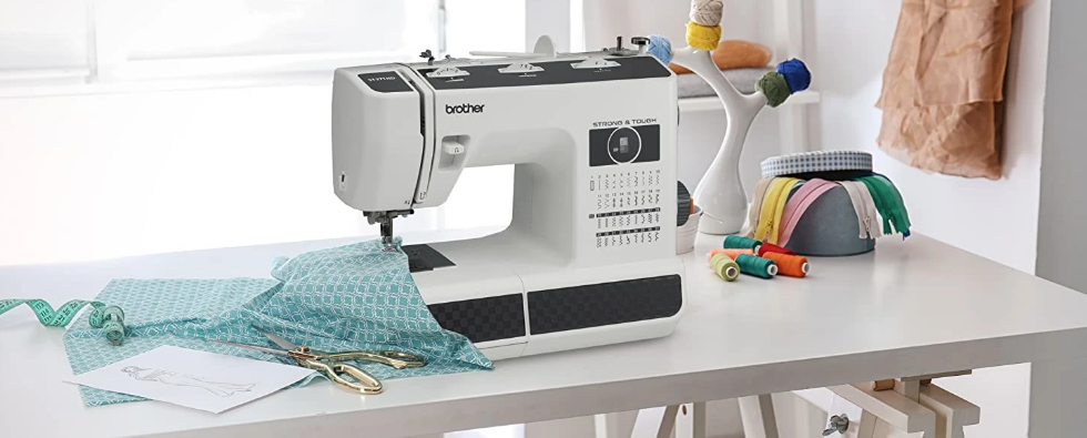 image of the Brother ST371HD Strong and Tough Computerized Sewing Machine on a table with sewing example and sewing supplies