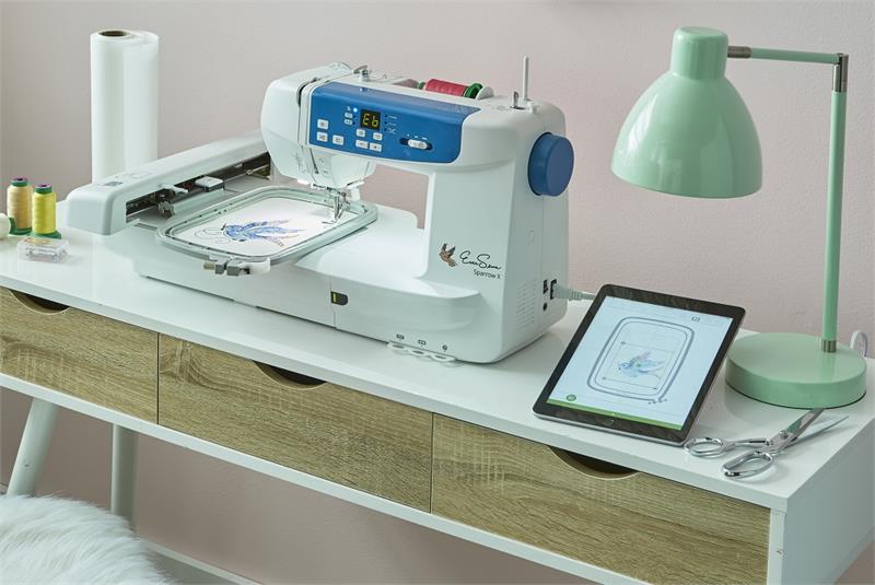 image of the EverSewn Sparrow X2 Sewing and Embroidery Combo Machine and a tablet connected to it on a table