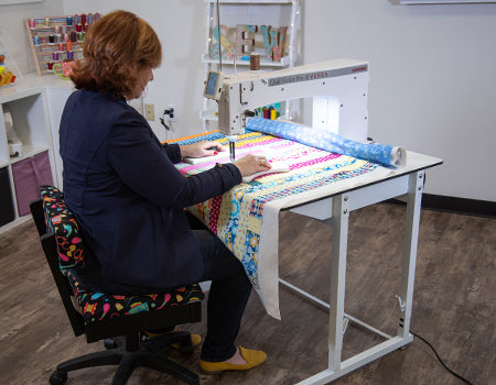 image of a woman using the Janome Quilt Maker Pro 18 Versa Longarm Quilting Machine