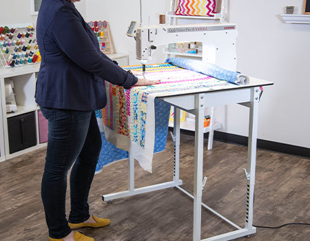 woman using the Janome Quilt Maker Pro 18 Versa Longarm Quilting Machine
